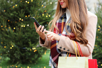 美丽的年轻的有吸引力的女人智能<strong>手机</strong>购物在线携带袋圣诞<strong>节</strong>时间