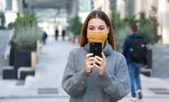 年轻的女人织物面具消息传递移动电话走行人街复制空间
