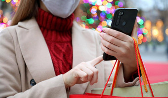 年轻的女人保护面具智能手机购物在线携带袋圣诞节时间裁剪图片焦点手电话