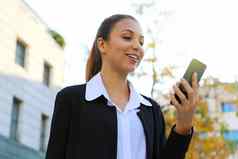 肖像快乐的年轻的业务女人阅读好新闻聪明的电话户外