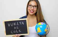 拉丁年轻的女老师持有全球黑板上西班牙语写回来科尔回来学校