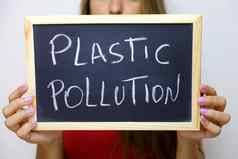 塑料污染写黑板上持有年轻的身份不明的女人