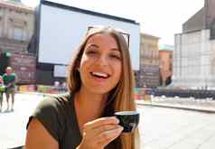 肖像微笑美丽的女人坐着在户外咖啡馆意大利喝咖啡