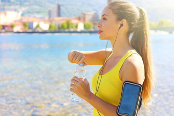 渴了健身女人打开瓶水培训户外适合女人智能手机健身应用程序手镯听音乐活动跟踪器