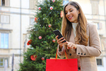 圣诞节女人购买在线聪明的电话走街圣诞节树背景