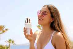微笑美丽的女孩太阳镜海滩吃冰奶油棕榈树背景夏天假期概念