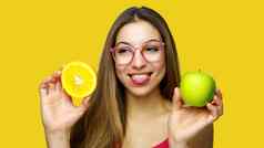积极的明亮的肖像漂亮的女人微笑显示舌头持有美味的水果一边时尚的夏天装橙色背景饮食素食主义者概念