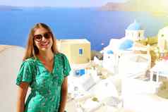 圣托里尼岛旅行旅游女人参观著名的白色村蓝色的穹顶aio希腊女孩绿色衣服太阳镜相机欧洲夏天目的地