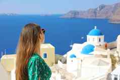 圣托里尼岛旅行旅游女人参观aio著名的白色村蓝色的穹顶希腊女孩绿色衣服太阳镜著名的蓝色的圆顶教堂欧洲目的地