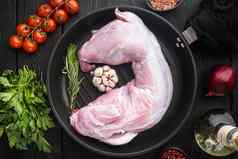 生新鲜的肉兔子准备好了烹饪成分投铁煎锅黑色的木表格背景前视图平躺