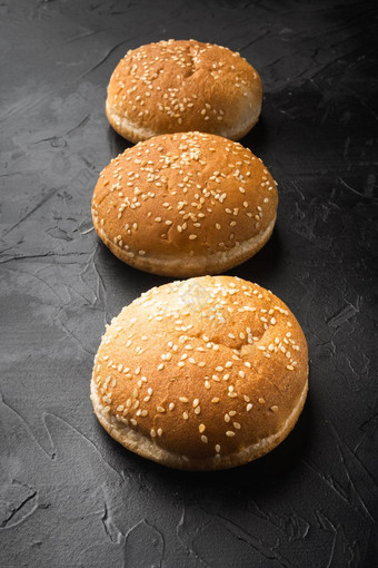 新鲜的自制的<strong>汉堡面包</strong>芝麻黑色的石头背景