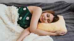 美丽的年轻的女孩绿色睡衣睡觉黄色的枕头
