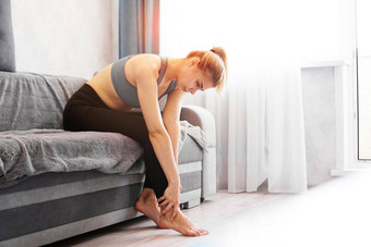 女人坐着沙发持有脚受伤感觉疼痛健康护理概念