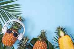 有趣的菠萝穿白色耳机概念听音乐孤立的彩色的背景热带棕榈叶子前视图平躺设计