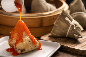 吃粽子龙船节日大米饺子年轻的亚洲女人吃中国人传统的食物木表格首页庆祝活动关闭