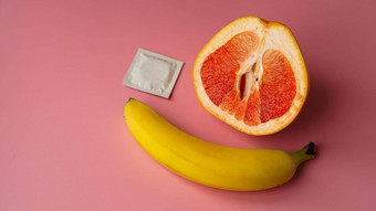 香蕉葡萄柚避孕套粉红色的背景