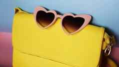 黄色的袋心形的太阳镜粉红色的蓝色的背景