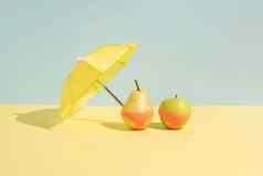 夏天水果概念湿苹果梨monokini伞孤立的蓝色的黄色的背景