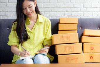 年轻的亚洲女人企业家电话写作订单客户在线笔记本<strong>首页</strong>在线购物<strong>物流</strong>交付女卖方工作沙发业务锻造