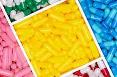 前视图黄色的蓝色的粉红色的红色的绿色白色胶囊药片塑料盒子纹理背景药店商店产品维生素补充抗生素药物选择胶囊药丸行业