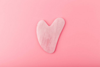 粉红色的心形状的<strong>刮痧</strong>疗法石头使石英水晶明亮的粉红色的背景