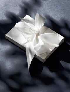 奢侈品假期白色礼物盒子丝绸丝带弓黑色的背景奢侈品婚礼生日现在