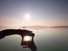 男人。手使影子符号太阳有雾的黎明湖
