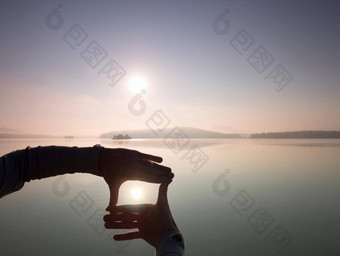 男人。手使影子符号太阳有雾的黎明湖