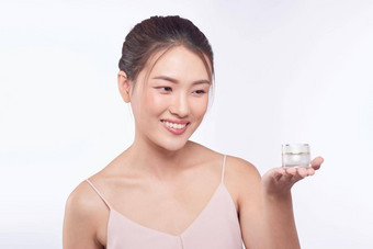 亚洲年轻的女人常备皮肤持有化妆品产品