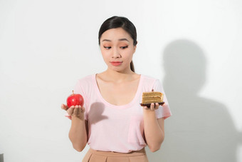 女人持有手蛋糕甜蜜的苹果水果选择<strong>抵制</strong>诱惑使饮食选择重量损失饮食两难的境地暴食概念