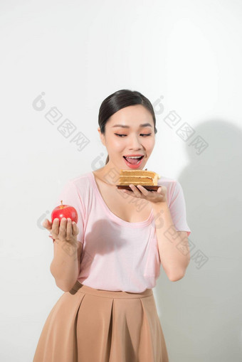 女人持有手蛋糕甜蜜的苹果水果选择抵制诱惑使饮食选择重量损失饮食两难的境地暴食概念