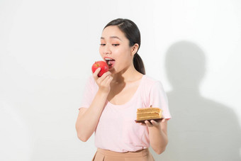 女人持有手蛋糕甜蜜的苹果水果选择<strong>抵制</strong>诱惑使饮食选择重量损失饮食两难的境地暴食概念
