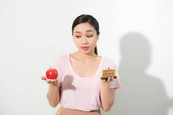 女人持有手蛋糕甜蜜的苹果水果选择抵制诱惑使饮食选择重量损失饮食两难的境地暴食概念
