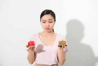 女人持有手蛋糕甜蜜的苹果水果选择抵制诱惑使<strong>饮食</strong>选择重量损失<strong>饮食</strong>两难的境地暴食概念