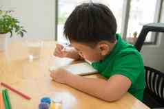 可爱的困惑微笑男孩家庭作业着色页面写作绘画孩子们油漆孩子们画学龄前儿童书图书馆色彩斑斓的铅笔纸桌子上有创意的男孩