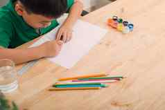 可爱的困惑微笑男孩家庭作业着色页面写作绘画孩子们油漆孩子们画学龄前儿童书图书馆色彩斑斓的铅笔纸桌子上有创意的男孩
