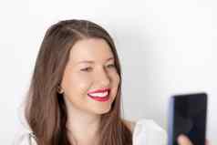 快乐微笑女人智能手机视频调用采取自拍肖像白色背景人技术沟通概念
