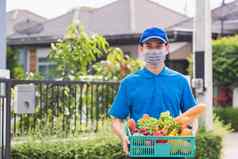 交付男人。穿脸面具保护交付新鲜的食物蔬菜塑料盒子