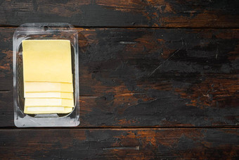 黄色的<strong>奶酪</strong>片切达干酪塑料<strong>包</strong>黑暗木表格背景前视图平躺复制空间文本