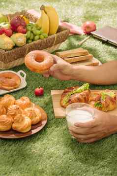 野餐柳条篮子食物面包水果橙色汁红色的白色检查布场绿色自然背景野餐概念