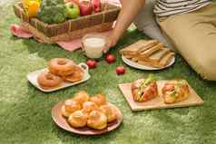野餐柳条篮子食物面包水果橙色汁红色的白色检查布场绿色自然背景野餐概念