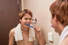 刷牙牙齿早....有吸引力的年轻的男人。刷牙牙齿牙刷镜子