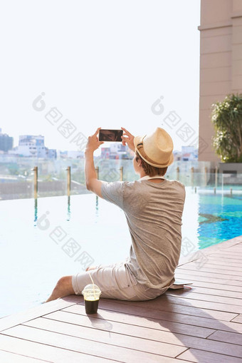 亚洲男人。智能手机照片游泳池背景