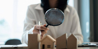 女人持有放大玻璃检查房子模型真正的房地产房子评估检查概念