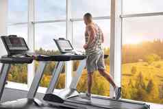 肌肉发达的运动健美运动员健身模型运行跑步机健身房大窗口