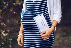 特写镜头怀孕了肚子蓝色的丝带标签开放怀孕了肚子光蓝色的丝带标签妈妈。期待