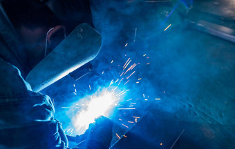 焊机焊接金属氩弧焊接机焊接火花男人。穿焊接面具保护手套安全工业工作场所焊机工作安全钢行业