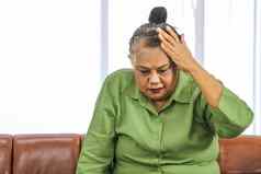 亚洲上了年纪的女人把握头疼痛坐着沙发房间