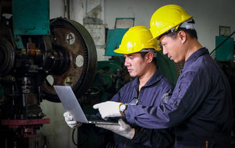 熟练的亚洲工人穿着头盔制服电脑