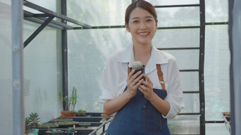 年轻的女人持有能仙人掌花手微笑笑采取护理